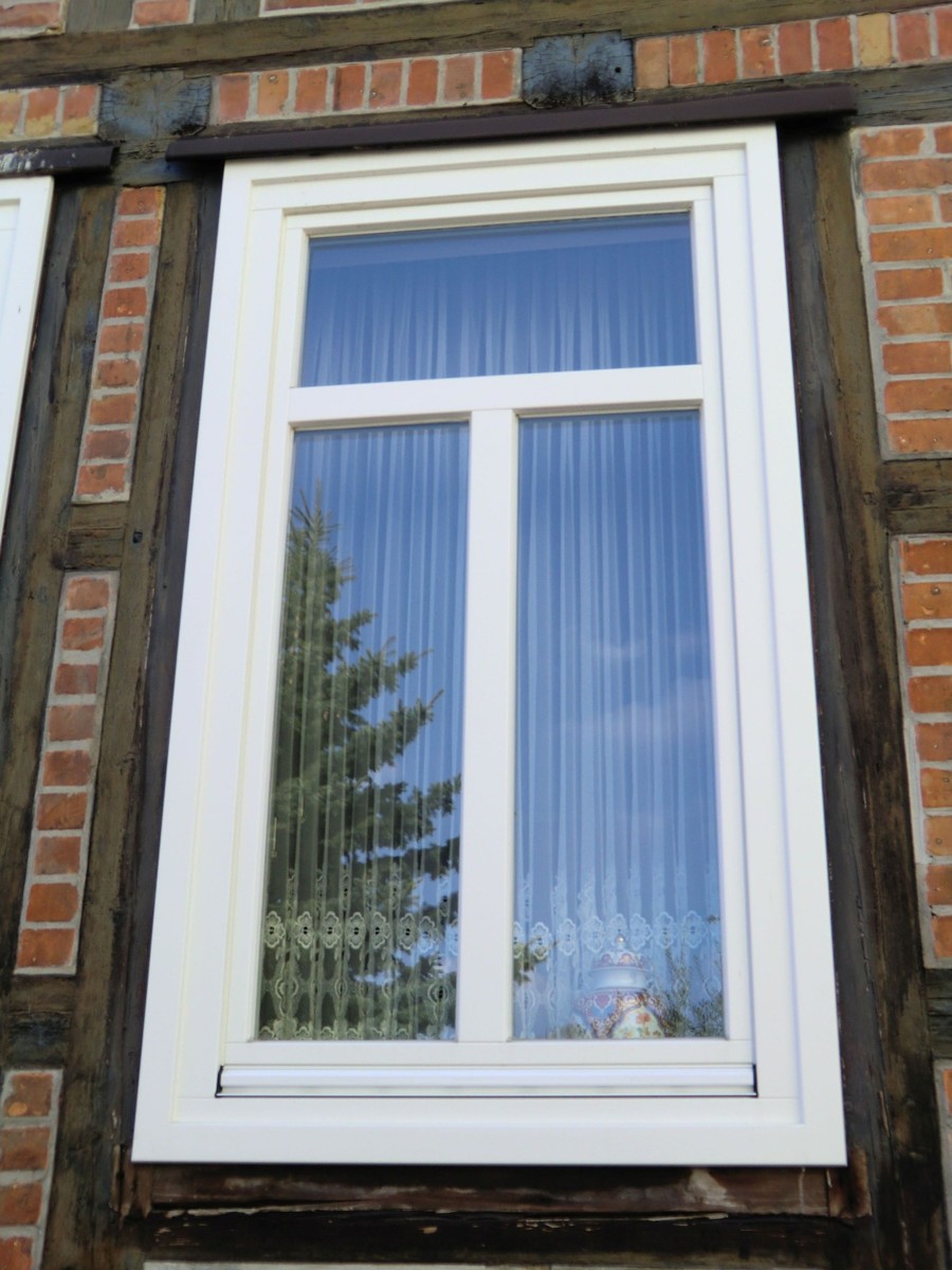 Weißes Fenster in einer Fachwerk- und Klinkerfassade